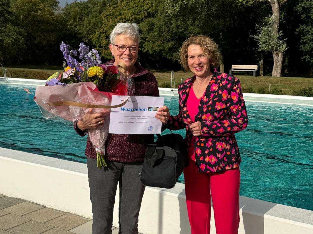Anneke Olthof met bos bloemen bij het zwembad in Sellingen, naast haar wethouder Giny Luth