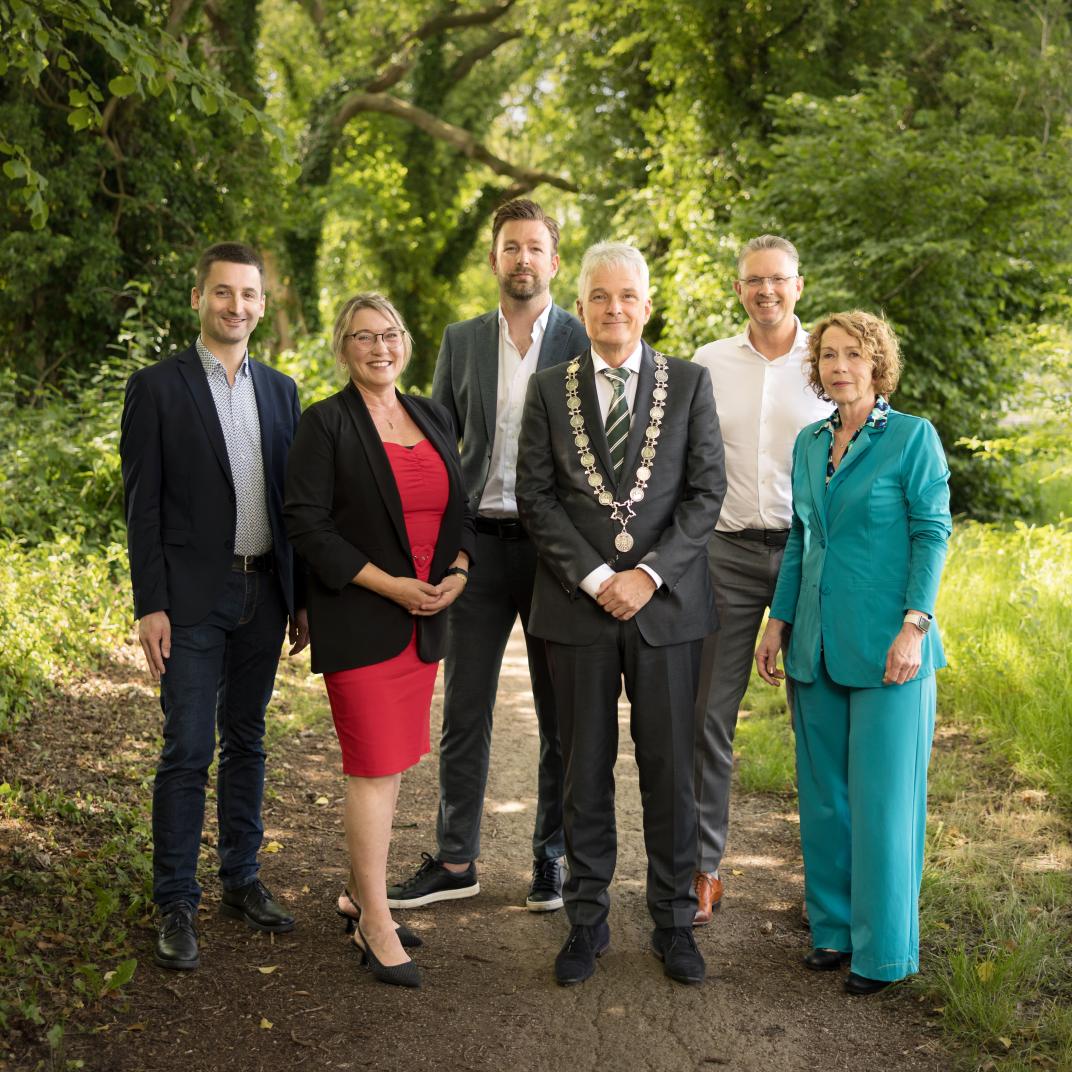 Collegeleden met op achtergrond groene natuur